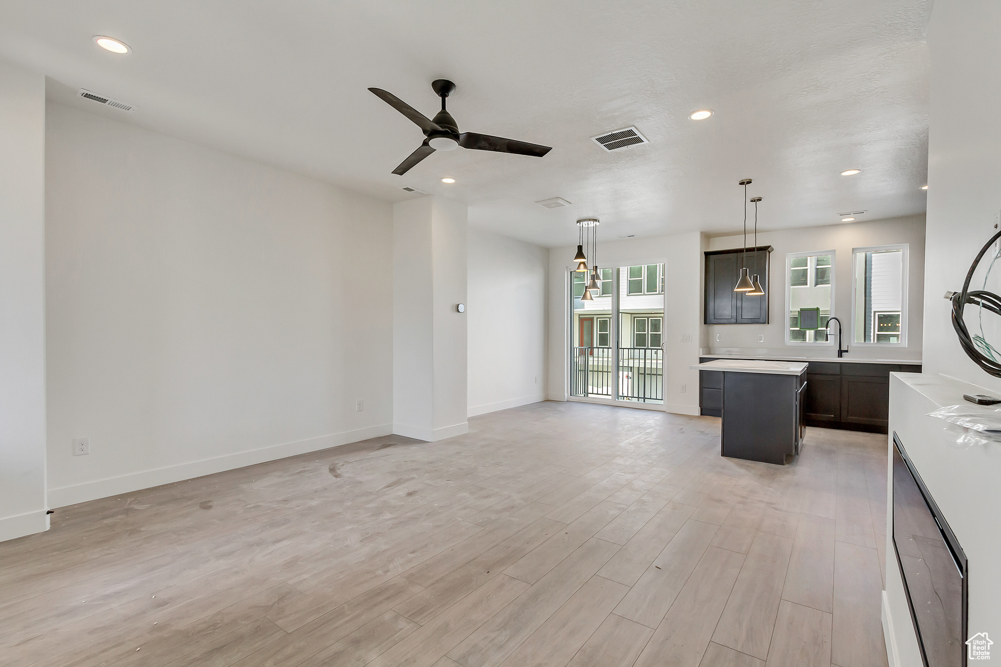 Unfurnished living room with sink, light hardwood / wood-style floors, and ceiling fan