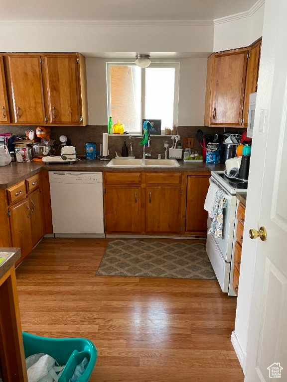 Kitchen with hardwood / wood-style floors, white appliances, tasteful backsplash, and sink