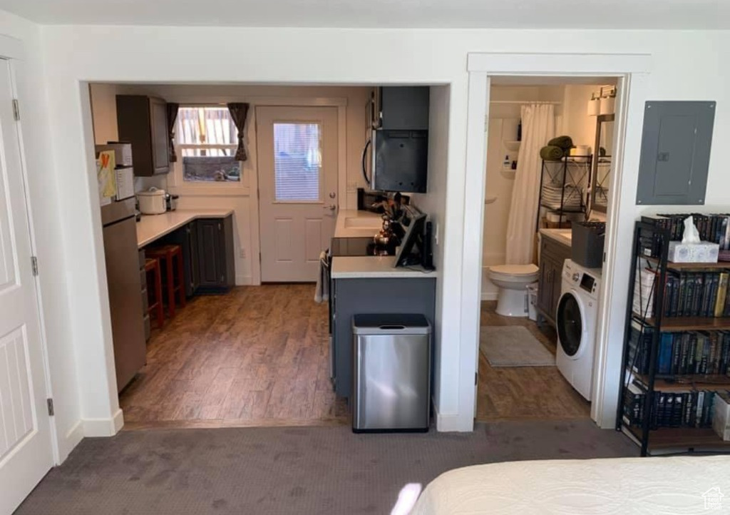 Carpeted bedroom featuring washer / dryer, connected bathroom, and stainless steel fridge