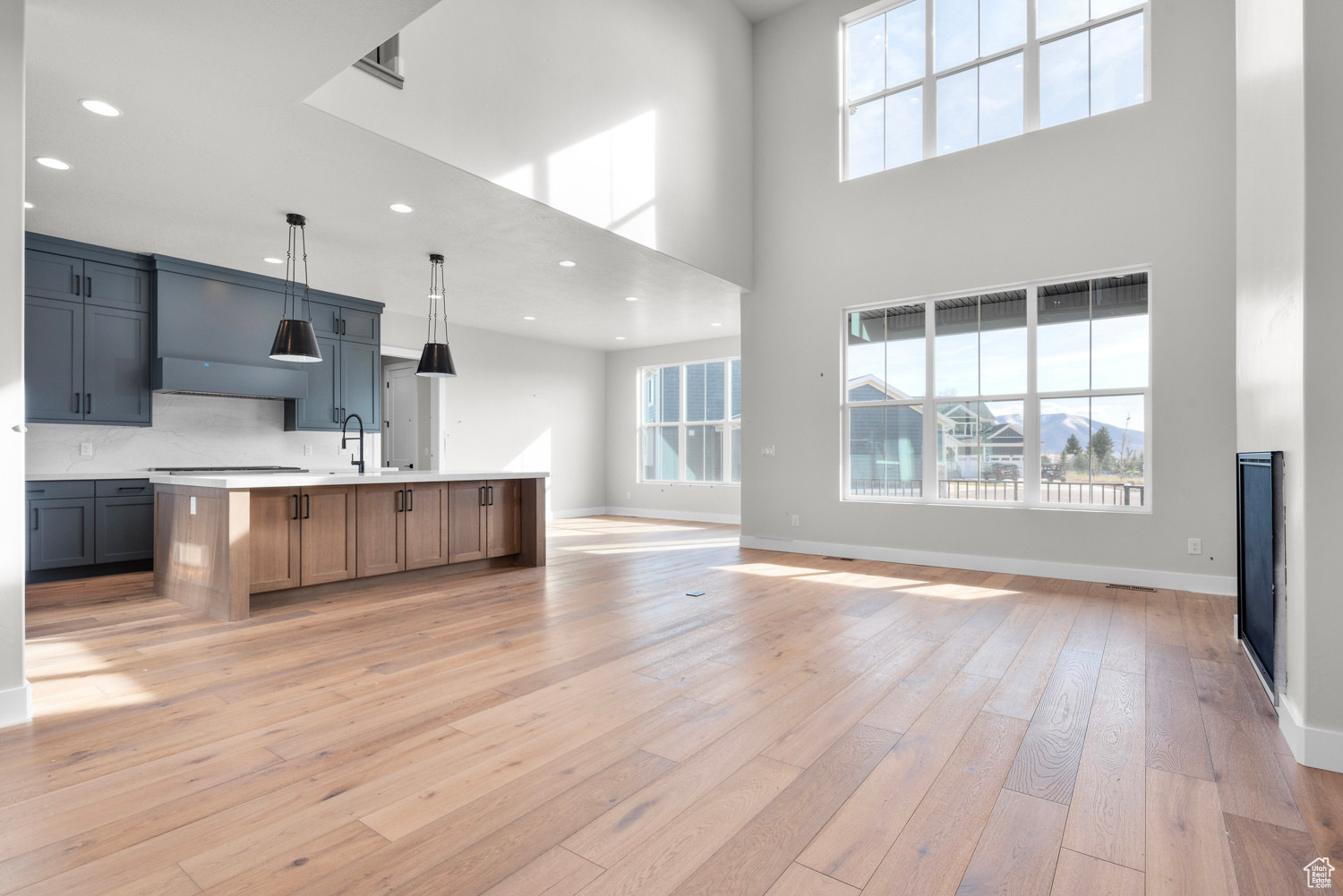 Kitchen featuring hanging light fixtures, light hardwood / wood-style flooring, tasteful backsplash, and a kitchen island with sink