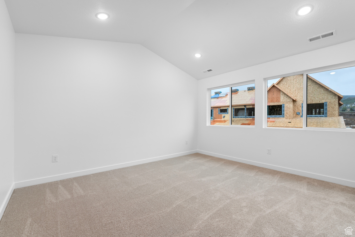 Empty room featuring vaulted ceiling and carpet