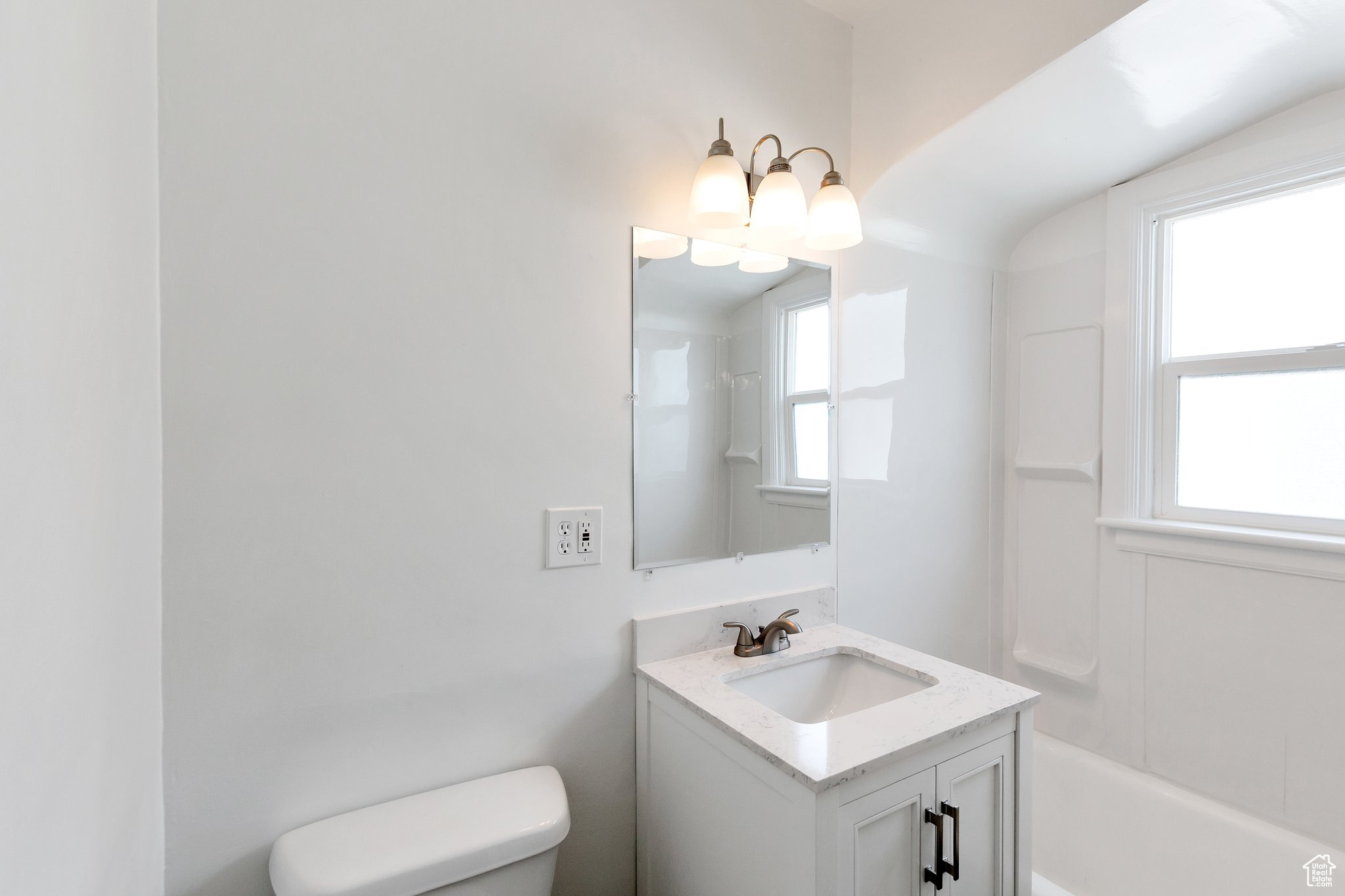 Full bathroom with a healthy amount of sunlight, toilet, shower / bathing tub combination, and large vanity