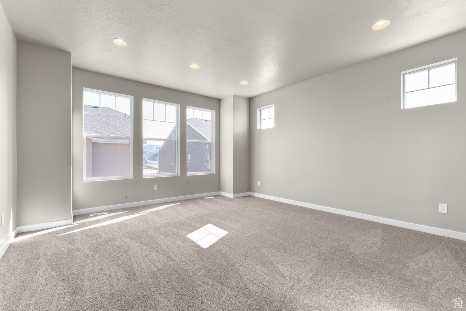 Unfurnished room featuring plenty of natural light and carpet flooring