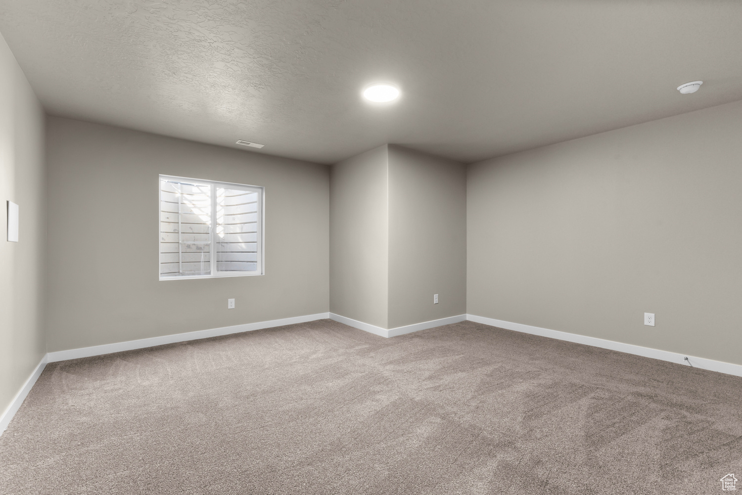 Spare room featuring carpet and a textured ceiling