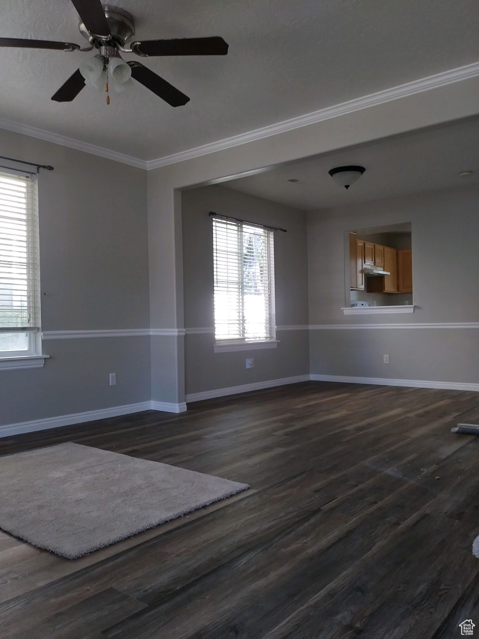 Empty room featuring crown molding, dark wood-type flooring, and ceiling fan