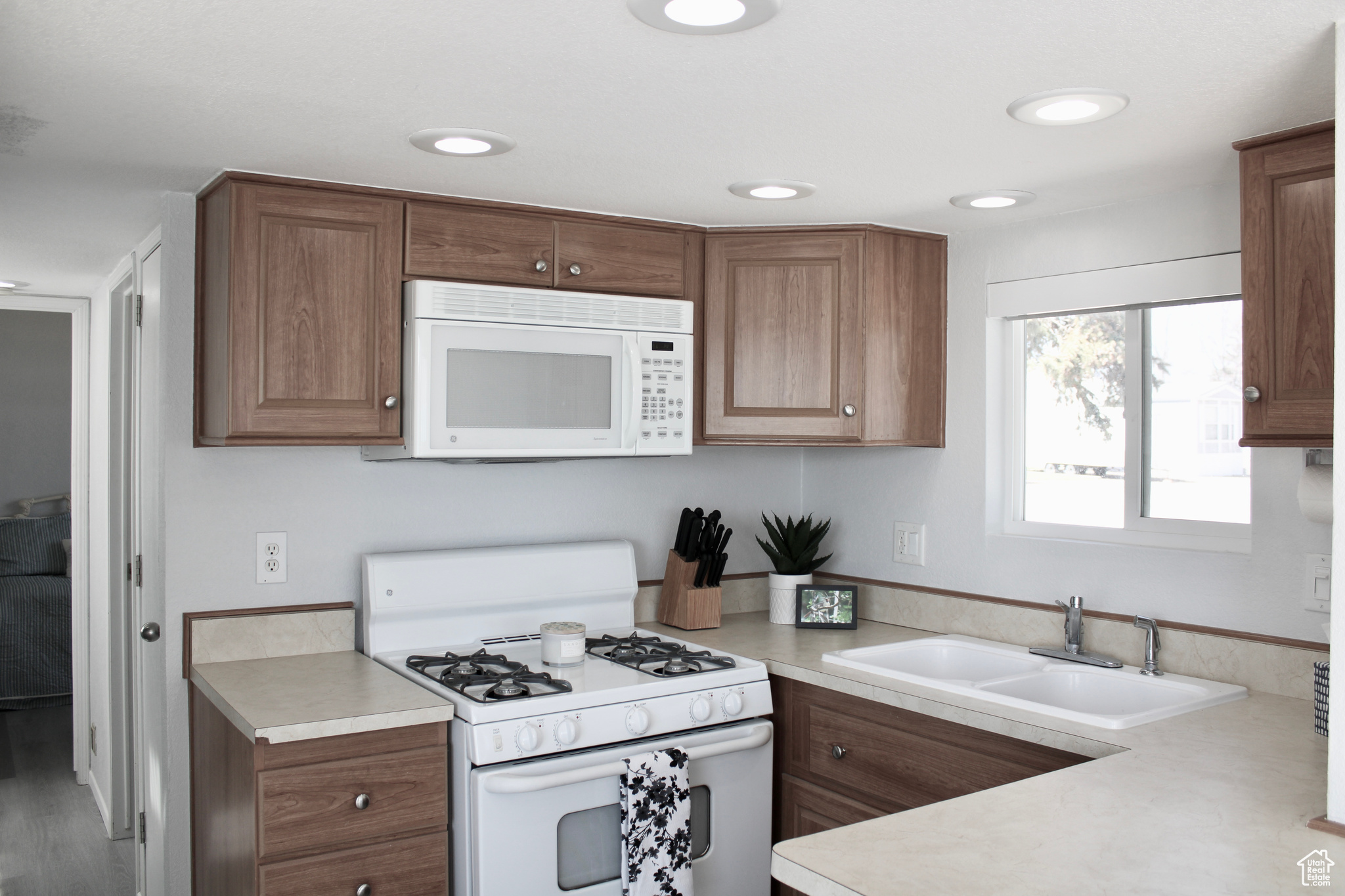 Kitchen with sink, white appliances, new LVP flooring.