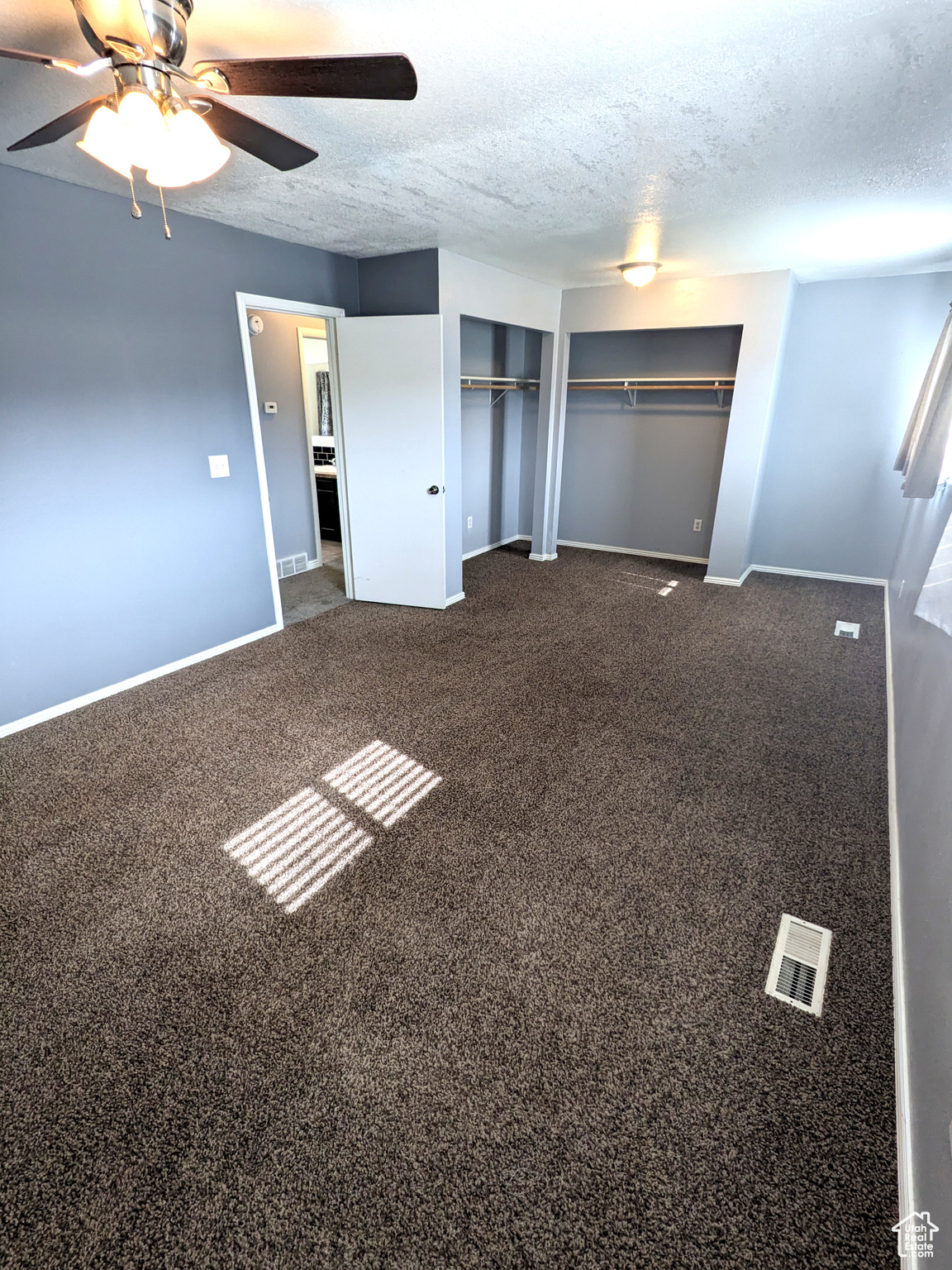 Unfurnished bedroom featuring ceiling fan, carpet floors, and a textured ceiling