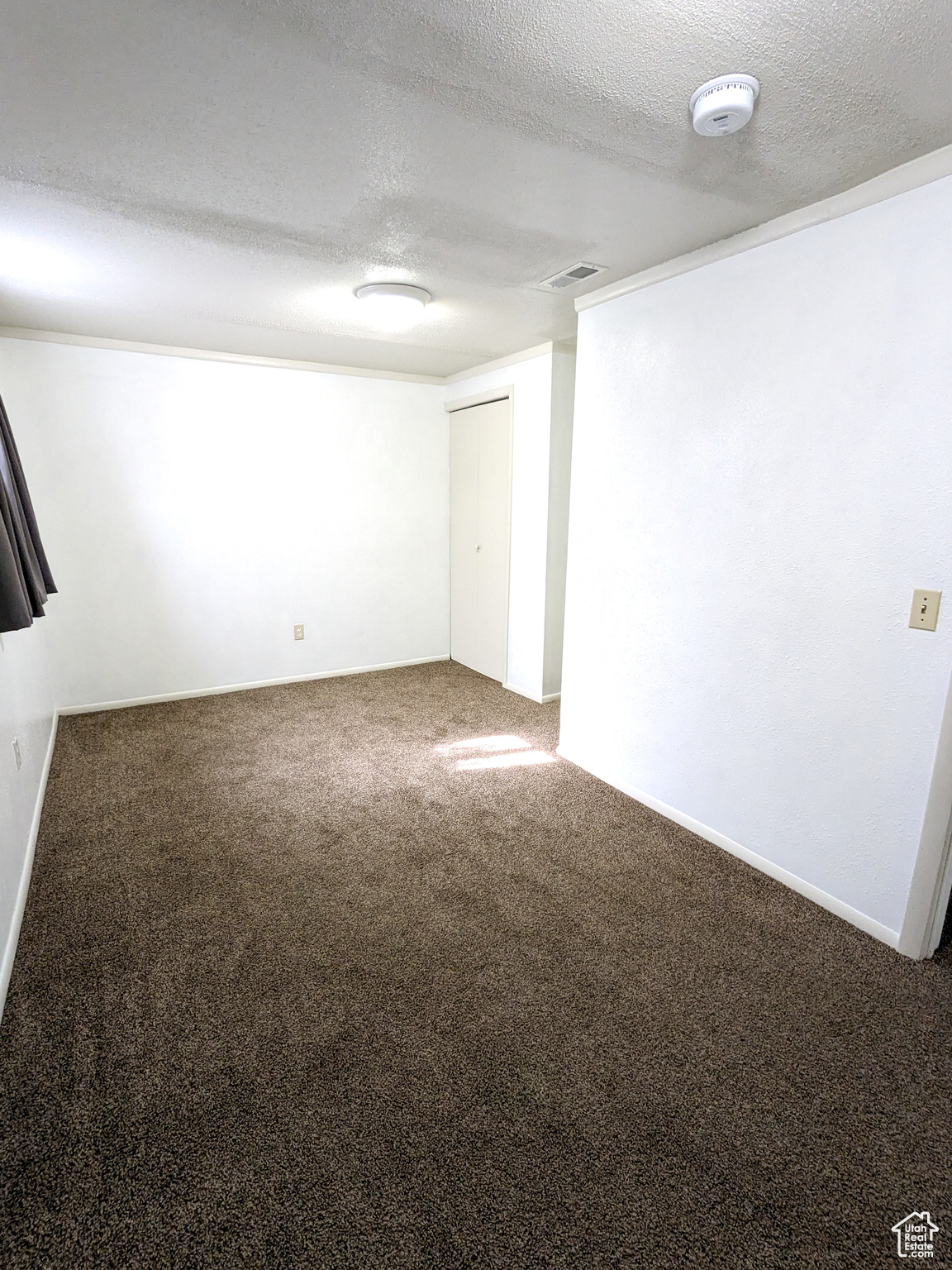 Empty room with carpet flooring and a textured ceiling