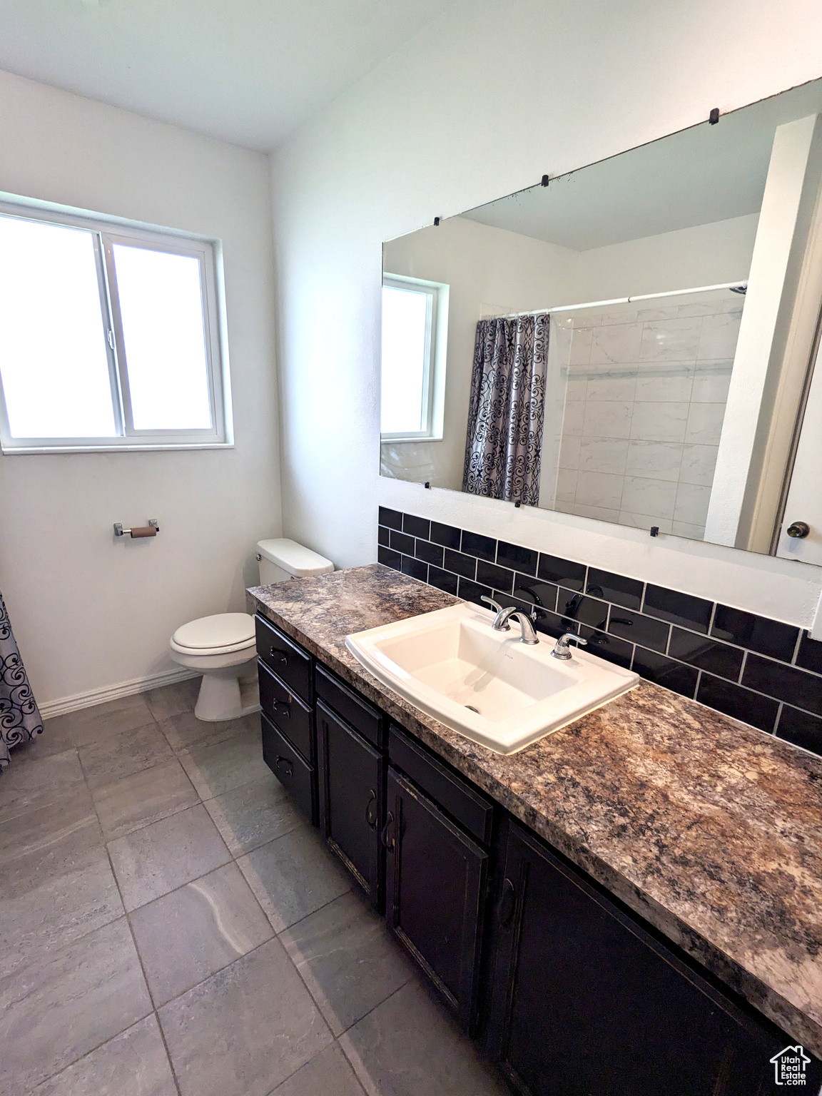 Bathroom featuring backsplash, a wealth of natural light, vanity, and toilet