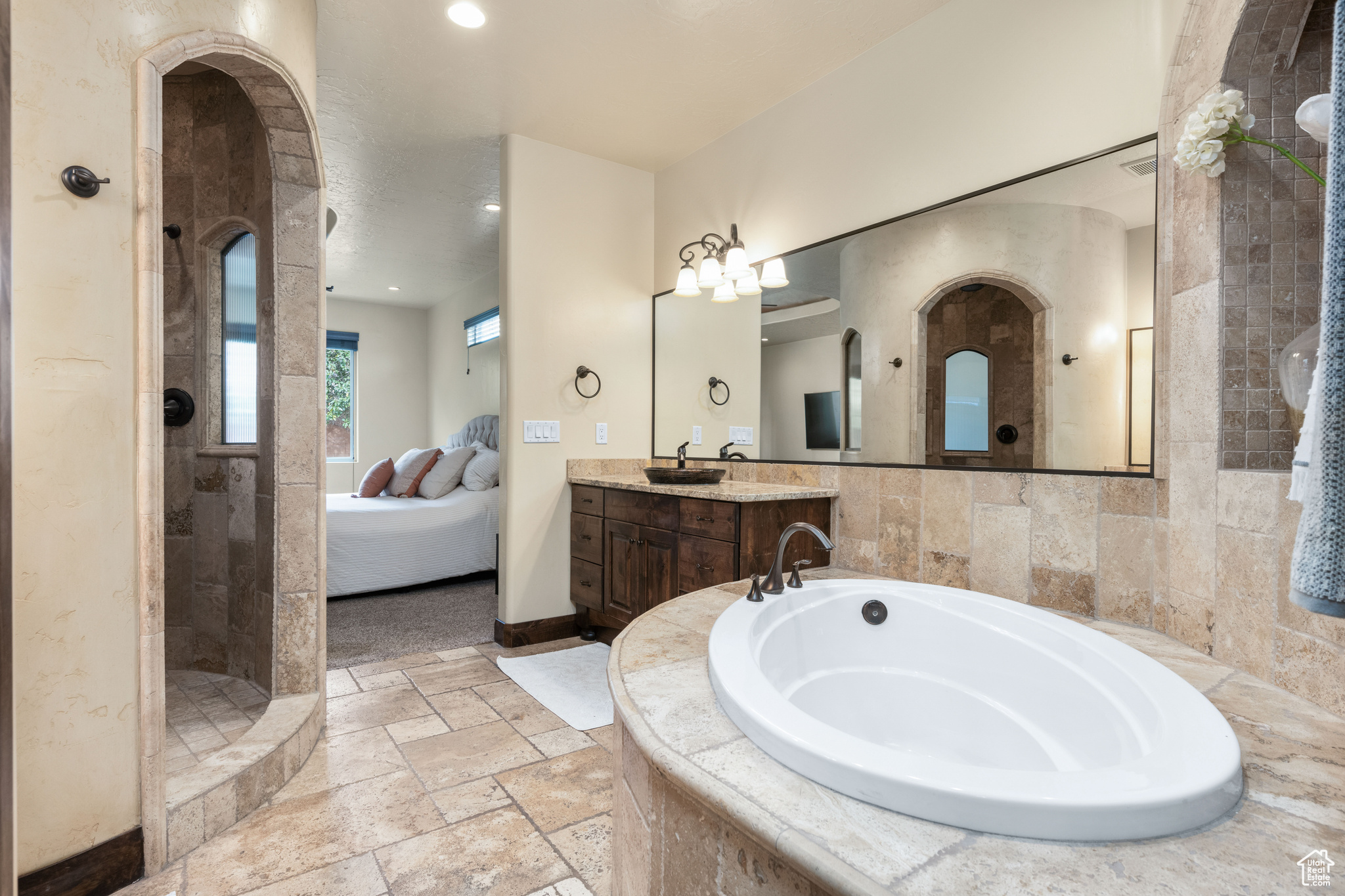 Bathroom with vanity with extensive cabinet space, separate shower and tub, tile floors, and tile walls