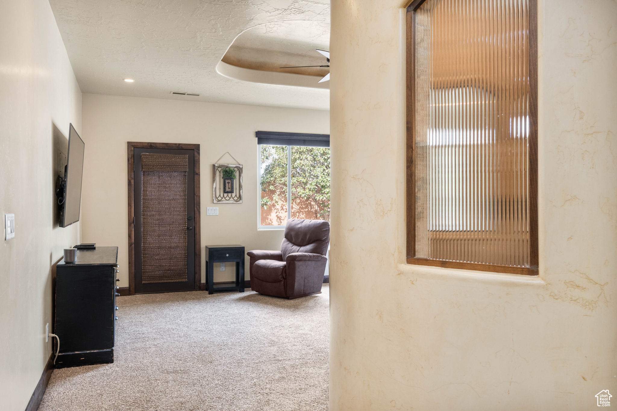 Interior space featuring ceiling fan, carpet floors, and a textured ceiling