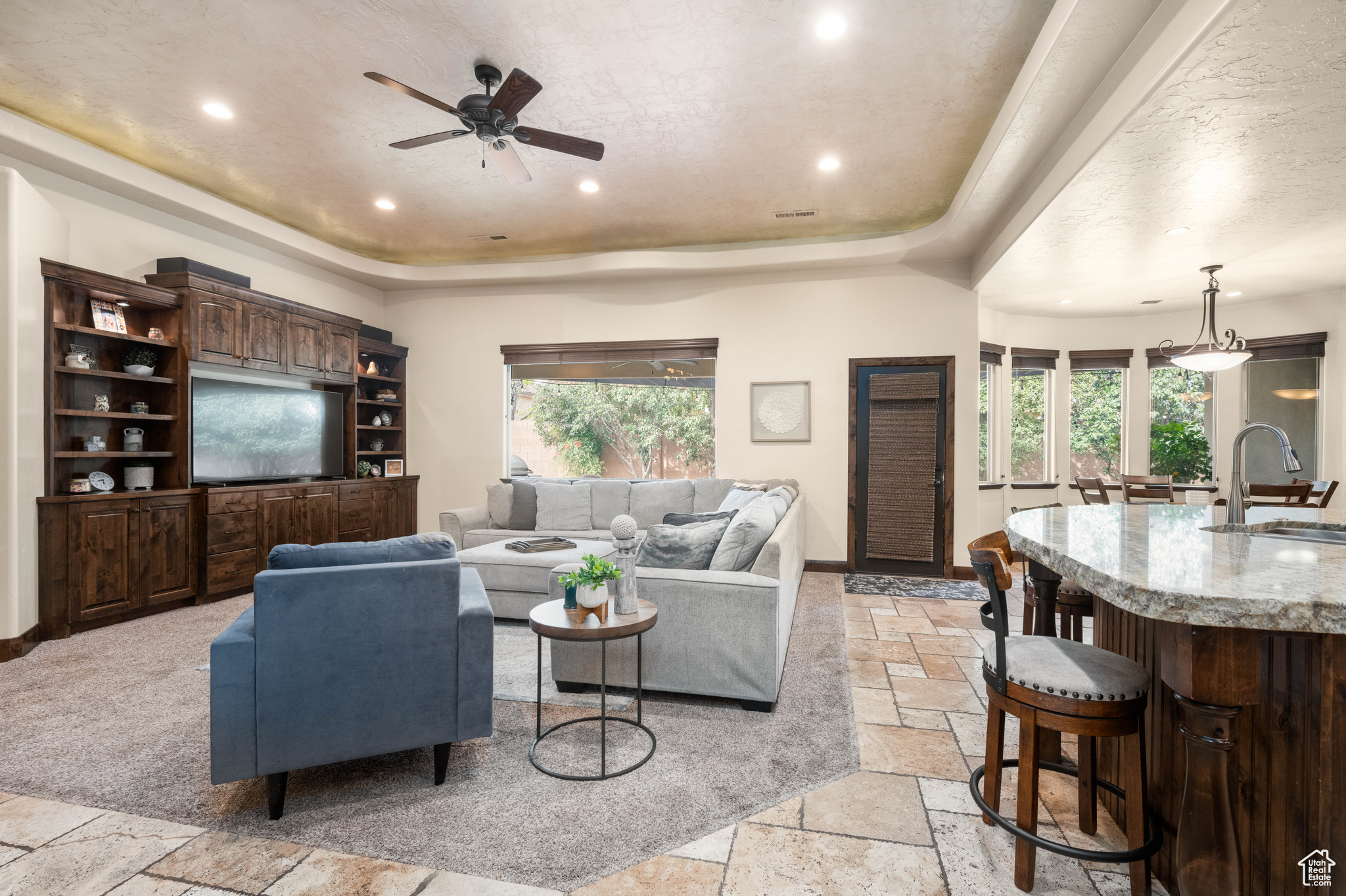 Carpeted living room with sink, ceiling fan, and a tray ceiling