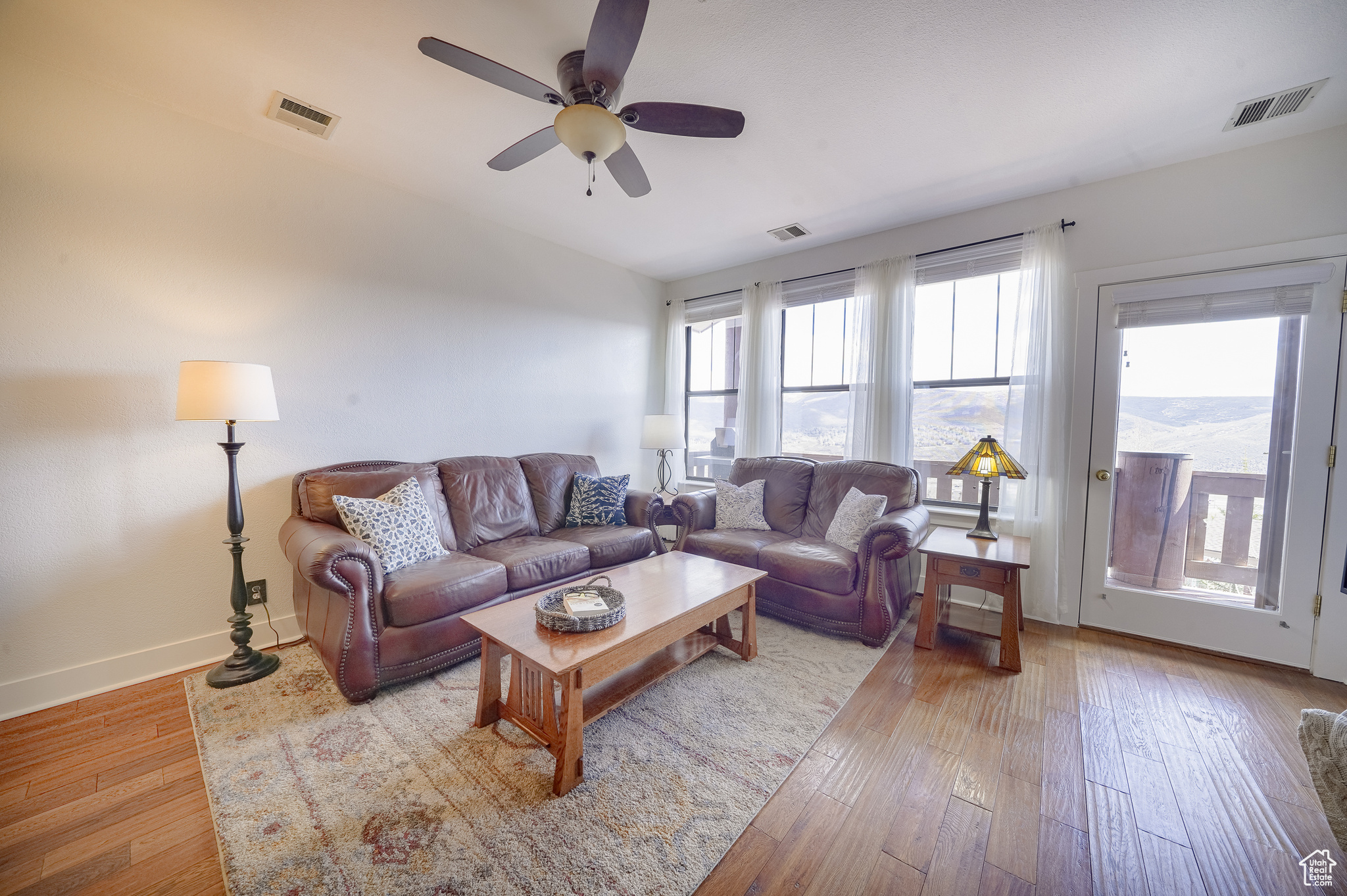 Living room with hardwood / wood-style flooring, plenty of natural light, and ceiling fan