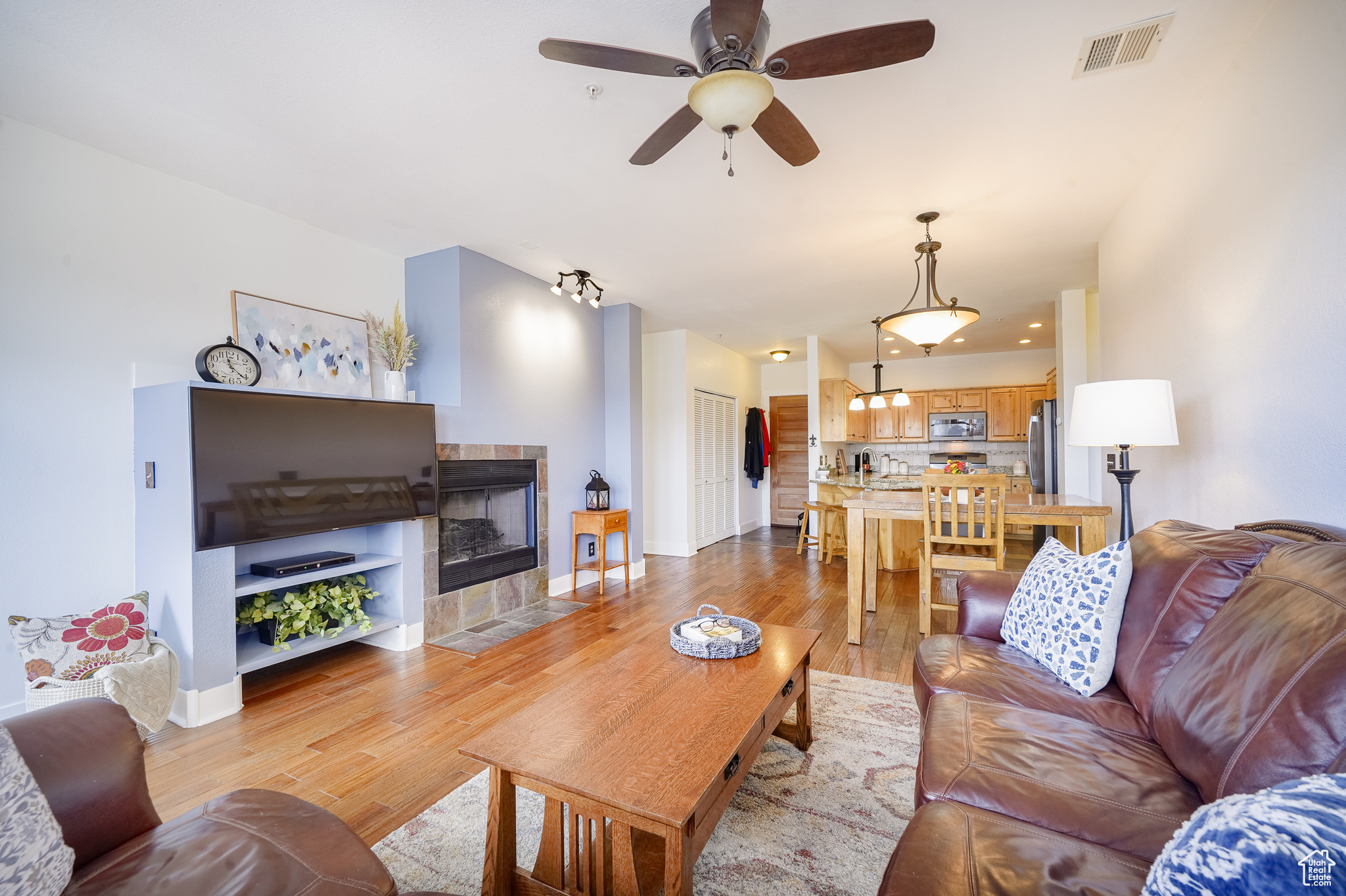 Living room featuring hardwood / wood-style flooring, ceiling fan, and a fireplace