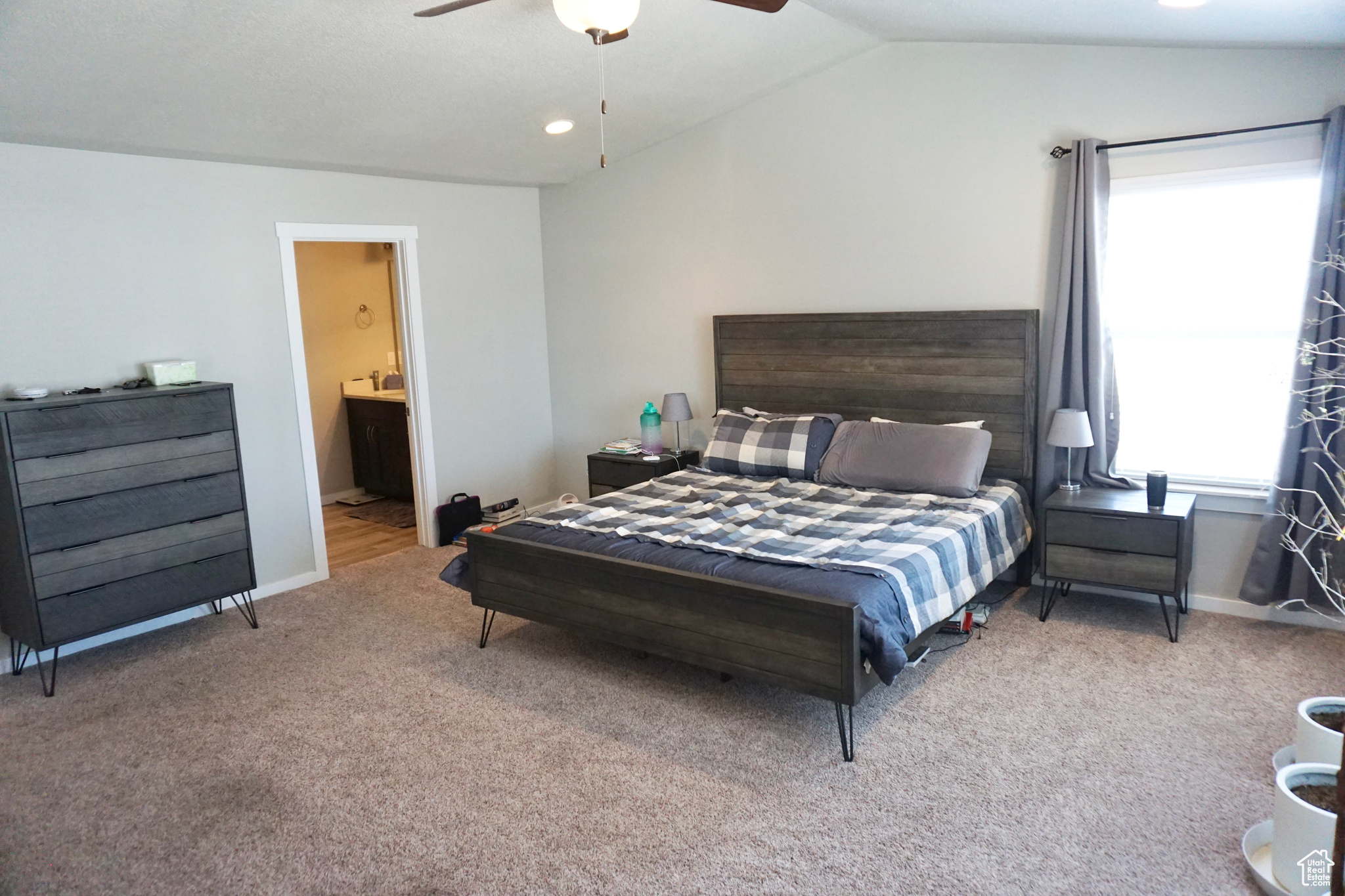 Bedroom featuring ensuite bath, ceiling fan, carpet floors, and lofted ceiling