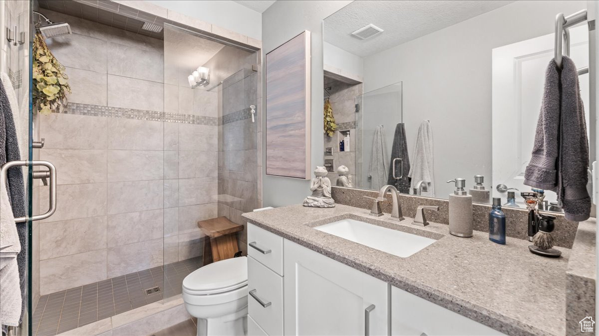 Bathroom with oversized vanity, an enclosed shower, and toilet