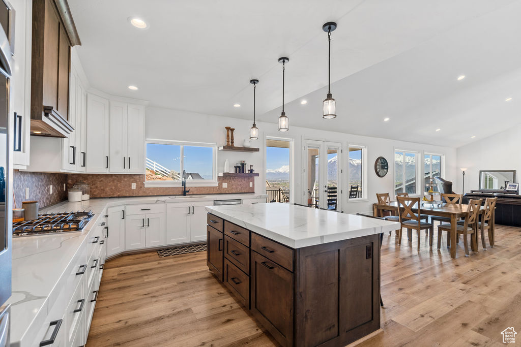 Kitchen with a wealth of natural light, light hardwood / wood-style flooring, decorative light fixtures, and a center island