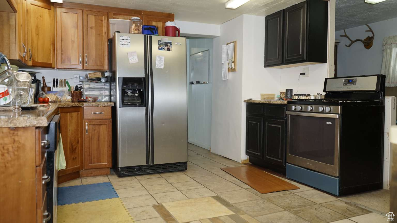 Kitchen featuring stainless steel appliances, light tile floors, and light stone counters