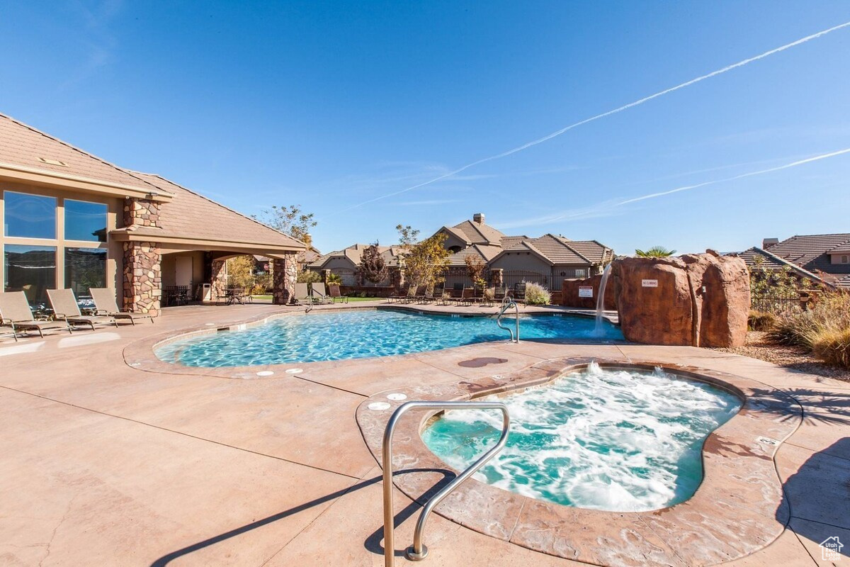 View of swimming pool featuring a community hot tub and a patio area with gym