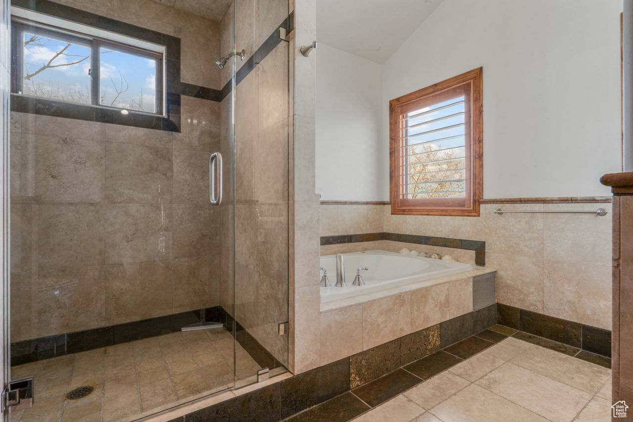 Bathroom with lofted ceiling, a wealth of natural light, and plus walk in shower