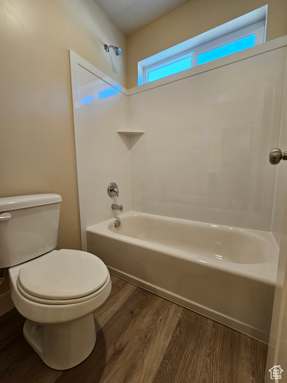 Bathroom with  shower combination, hardwood / wood-style flooring, and toilet