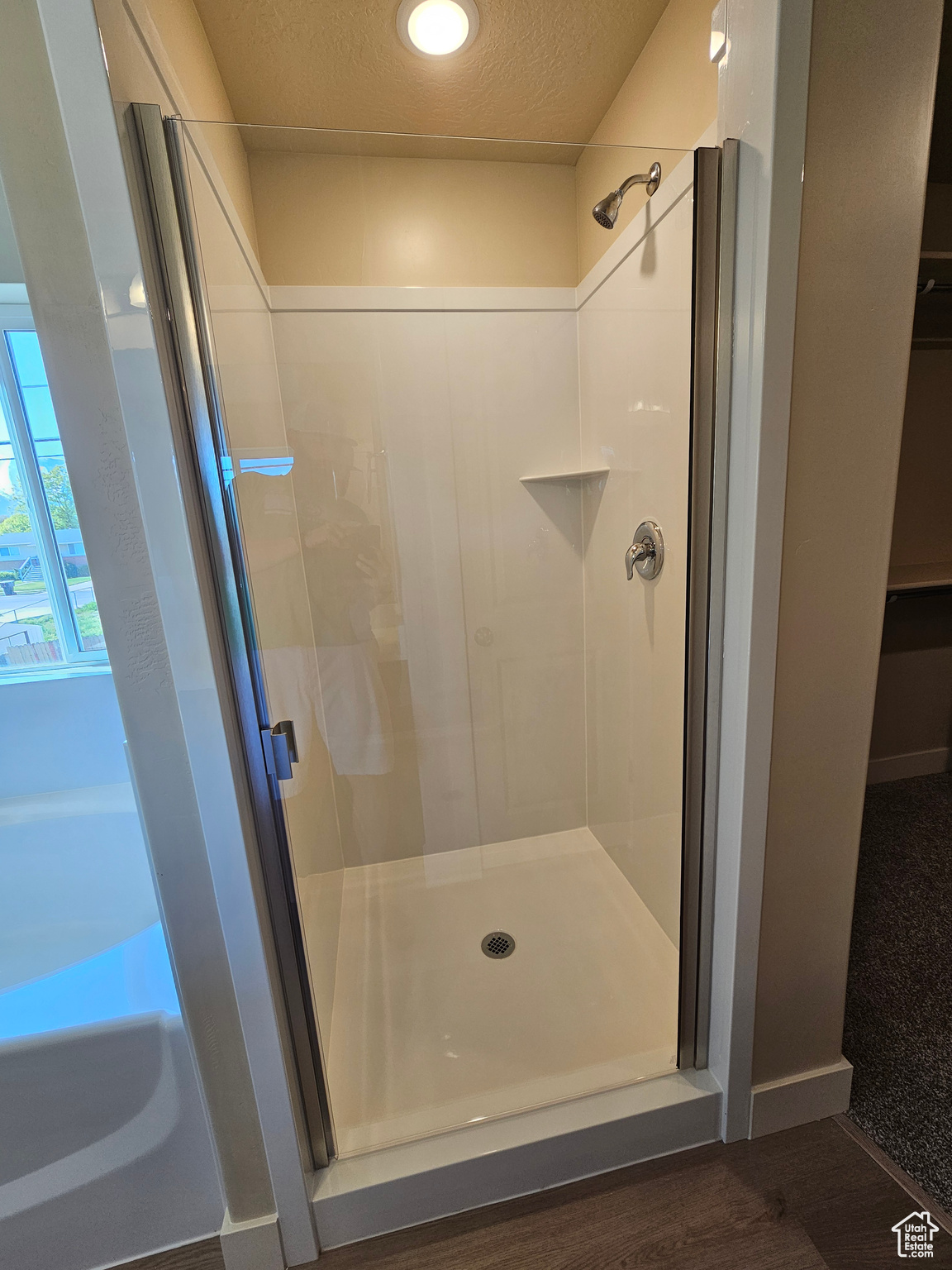 Bathroom with a textured ceiling, hardwood / wood-style flooring, and separate shower and tub