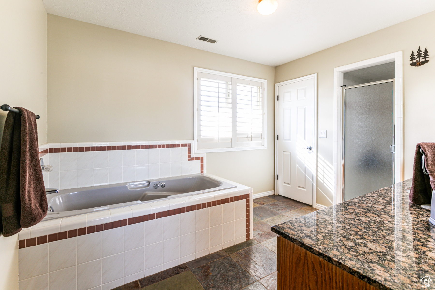 Bathroom featuring shower with separate bathtub, tile flooring, and vanity