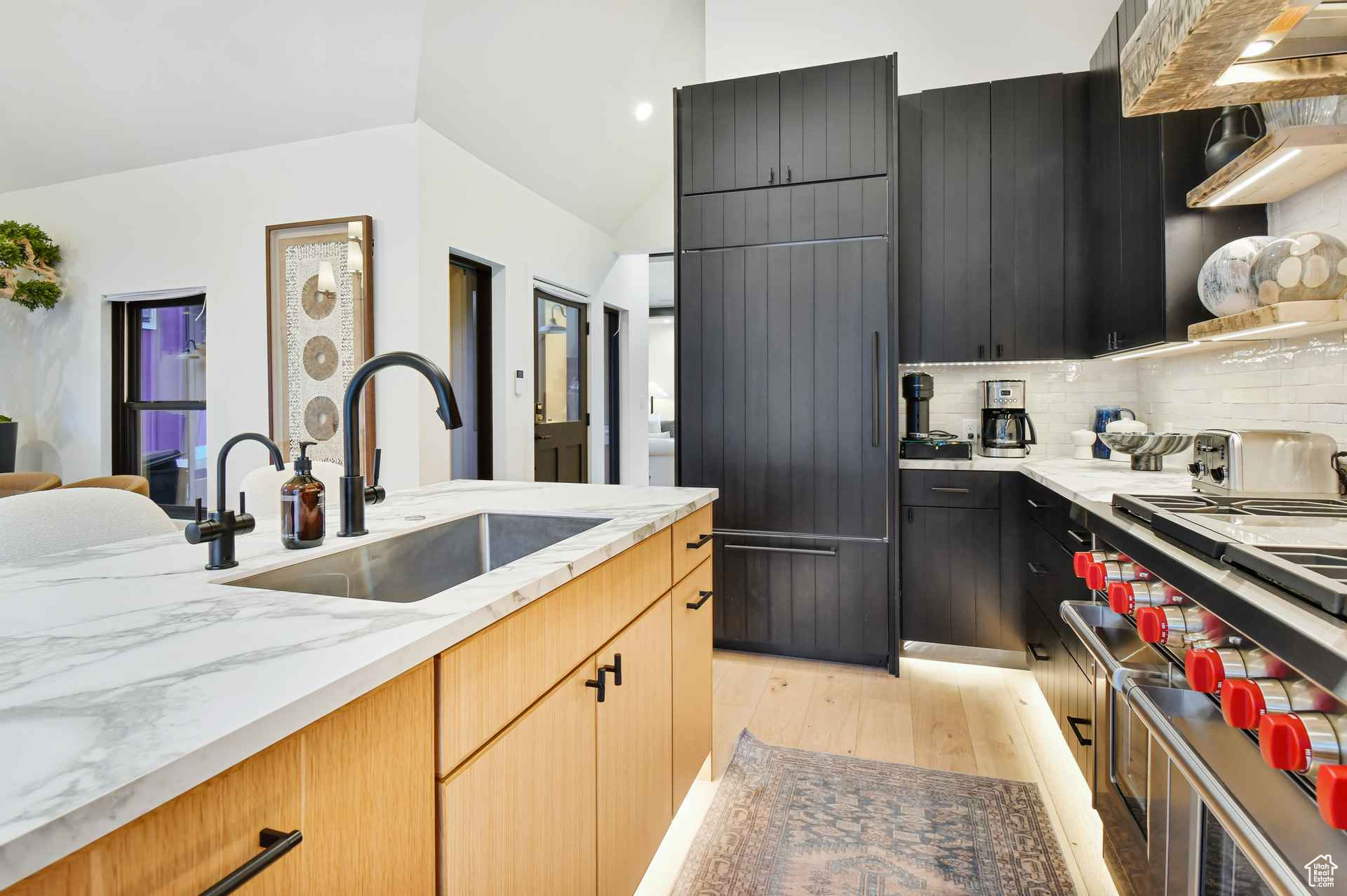 Kitchen featuring sink, light hardwood / wood-style flooring, backsplash, and light stone countertops