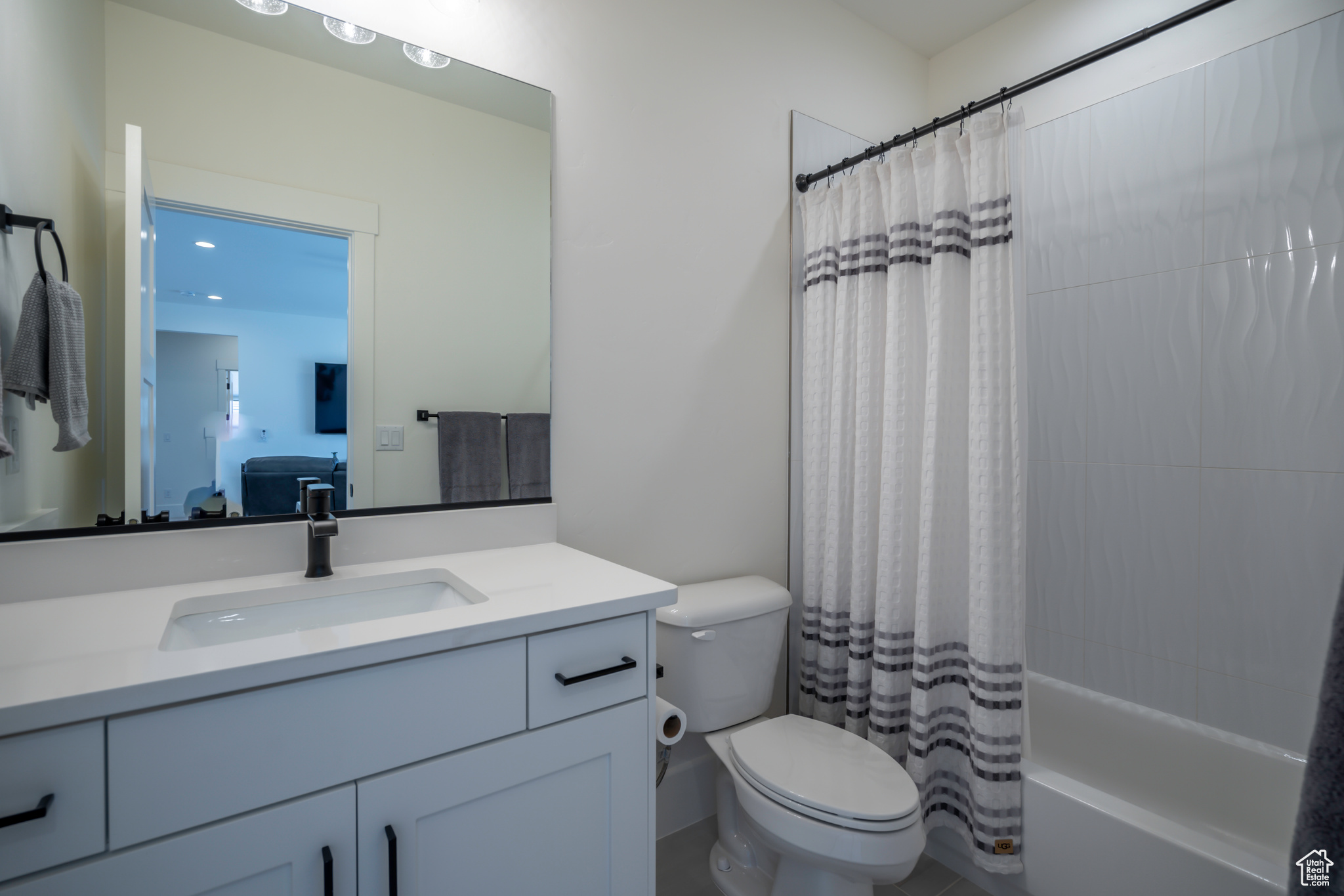 Full bathroom featuring vanity with extensive cabinet space, toilet, and shower / tub combo with curtain