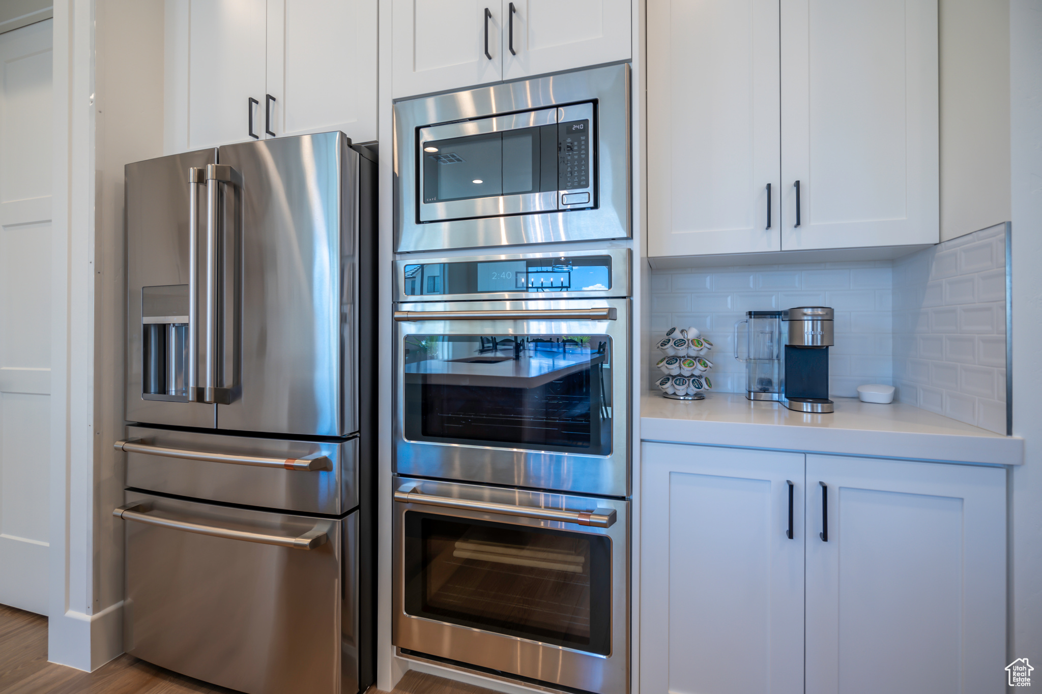 Kitchen featuring white cabinets, light hardwood / wood-style floors, tasteful backsplash, and stainless steel appliances