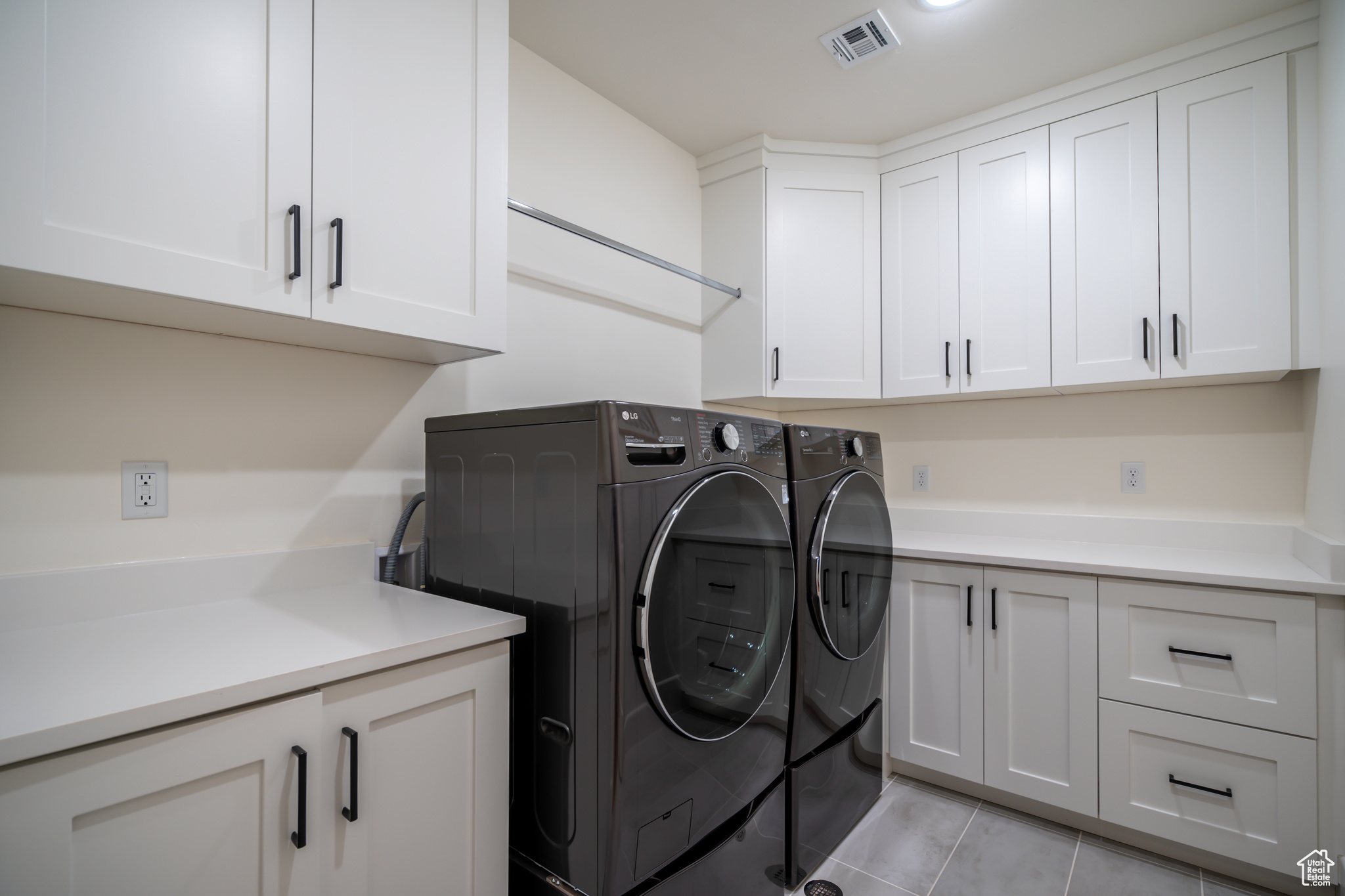 Washroom with independent washer and dryer, cabinets, and light tile floors