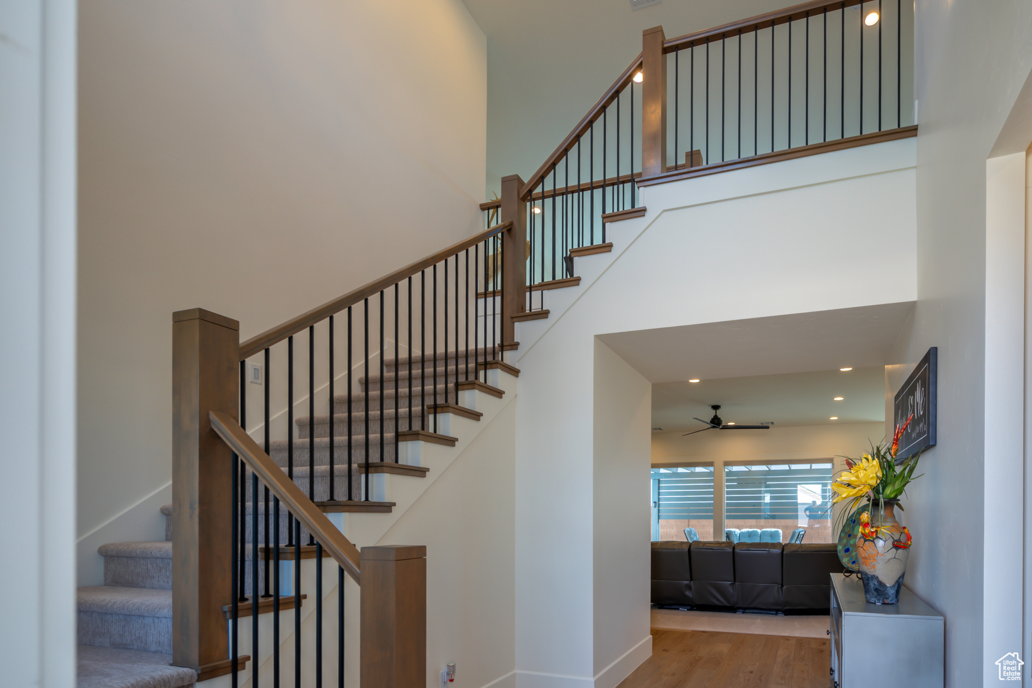 Stairs featuring hardwood / wood-style floors, ceiling fan, and a towering ceiling