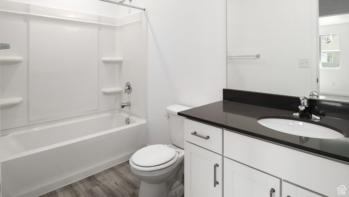 Full bathroom with shower / bath combination, toilet, vanity, and hardwood / wood-style floors