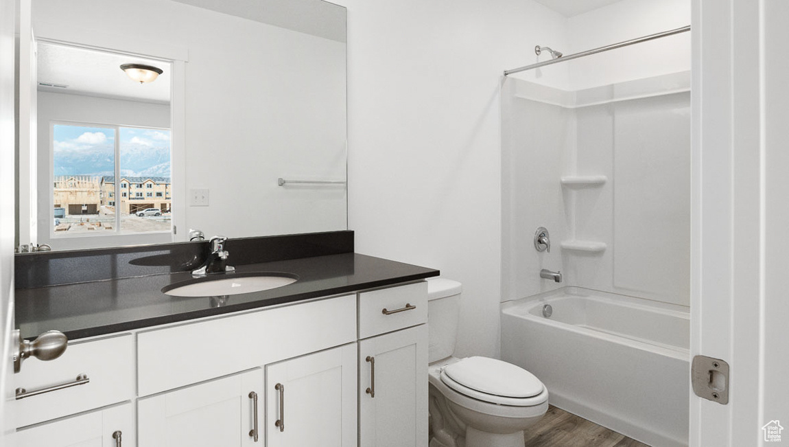 Full bathroom with bathtub / shower combination, hardwood / wood-style flooring, vanity, and toilet