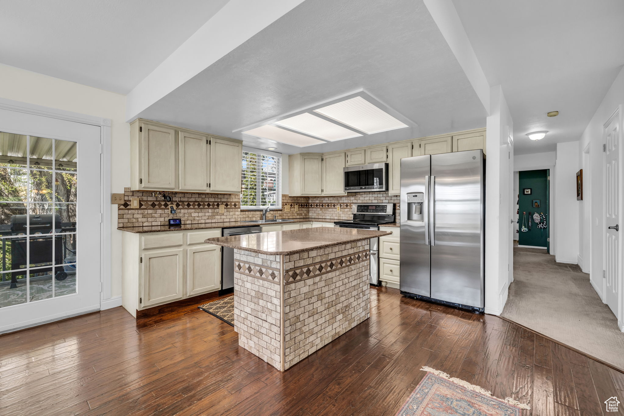 Kitchen featuring tasteful backsplash, stainless steel appliances, a center island, and dark wood-type flooring