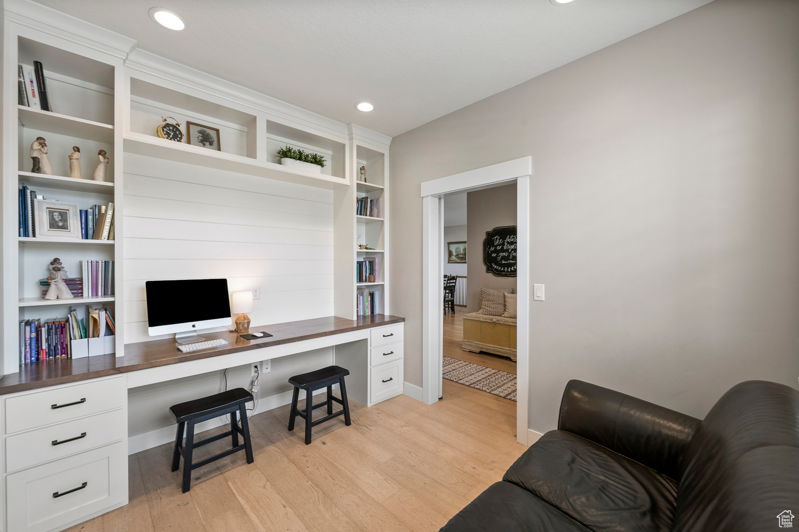 Home office with built in desk and light hardwood / wood-style floors