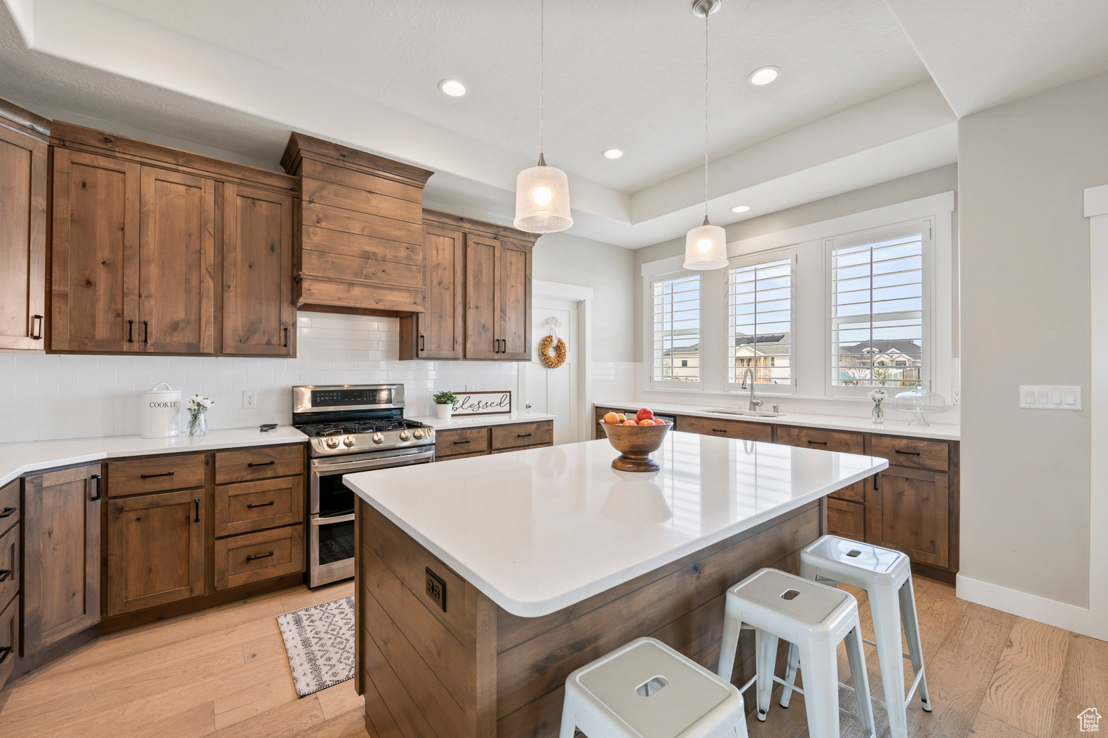 Kitchen with decorative light fixtures, light hardwood / wood-style flooring, double oven range, custom range hood, and a kitchen island