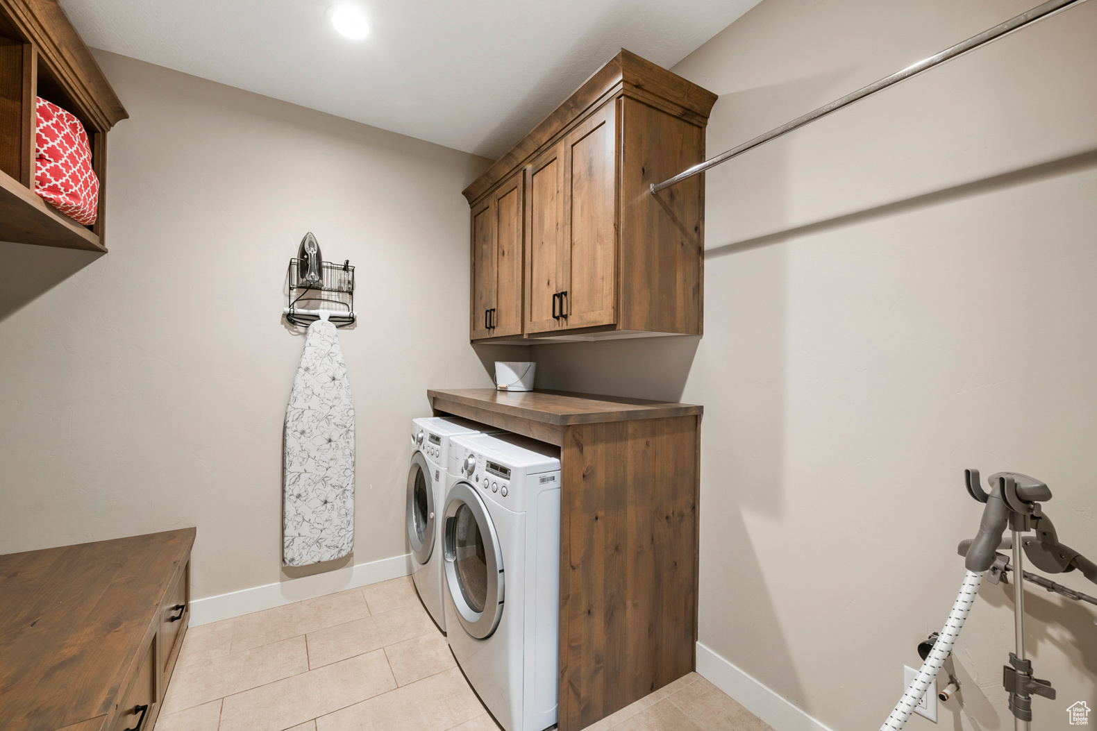 Laundry room with independent washer and dryer, cabinets, and light tile floors