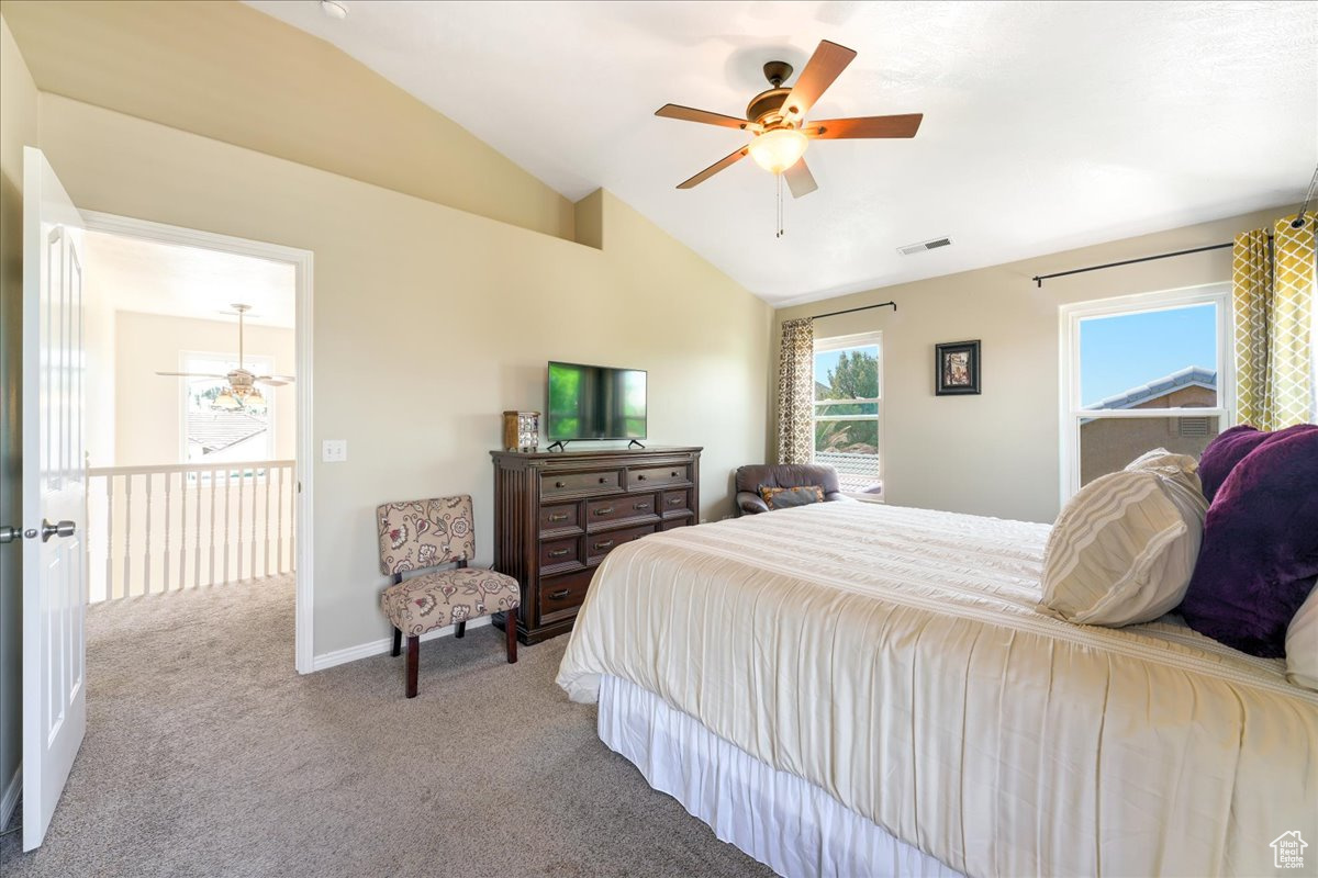 Bedroom featuring vaulted ceiling, ceiling fan, and carpet flooring