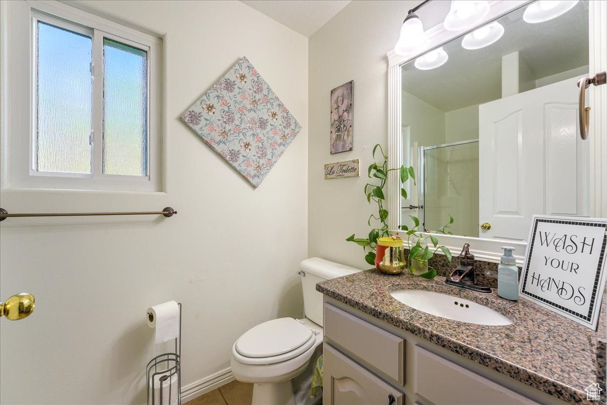 Bathroom featuring a healthy amount of sunlight, toilet, tile floors, and large vanity