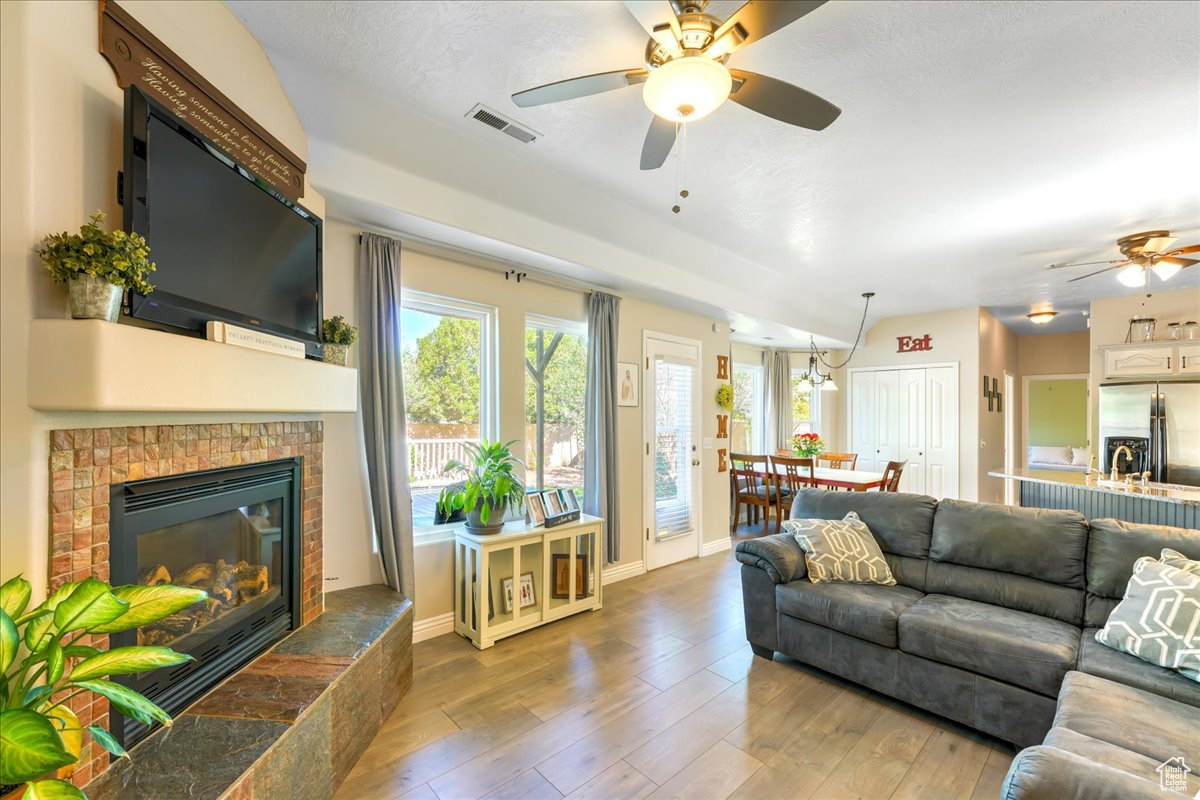 Living room with hardwood / wood-style flooring, ceiling fan, and a fireplace