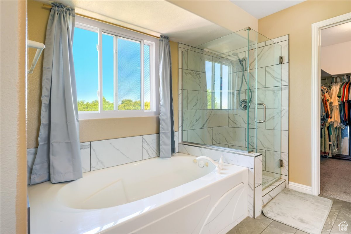 Bathroom featuring a healthy amount of sunlight, shower with separate bathtub, and tile floors