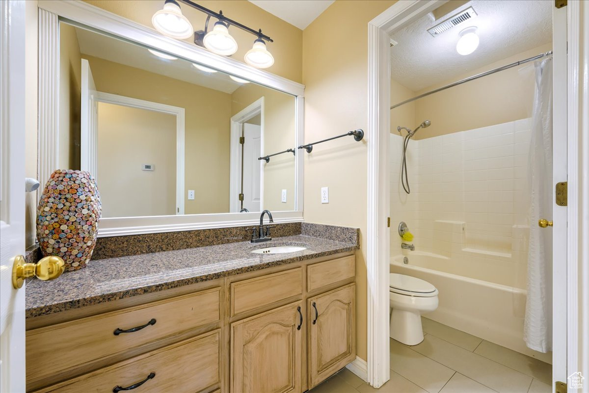 Full bathroom featuring oversized vanity, shower / tub combo, toilet, and tile flooring