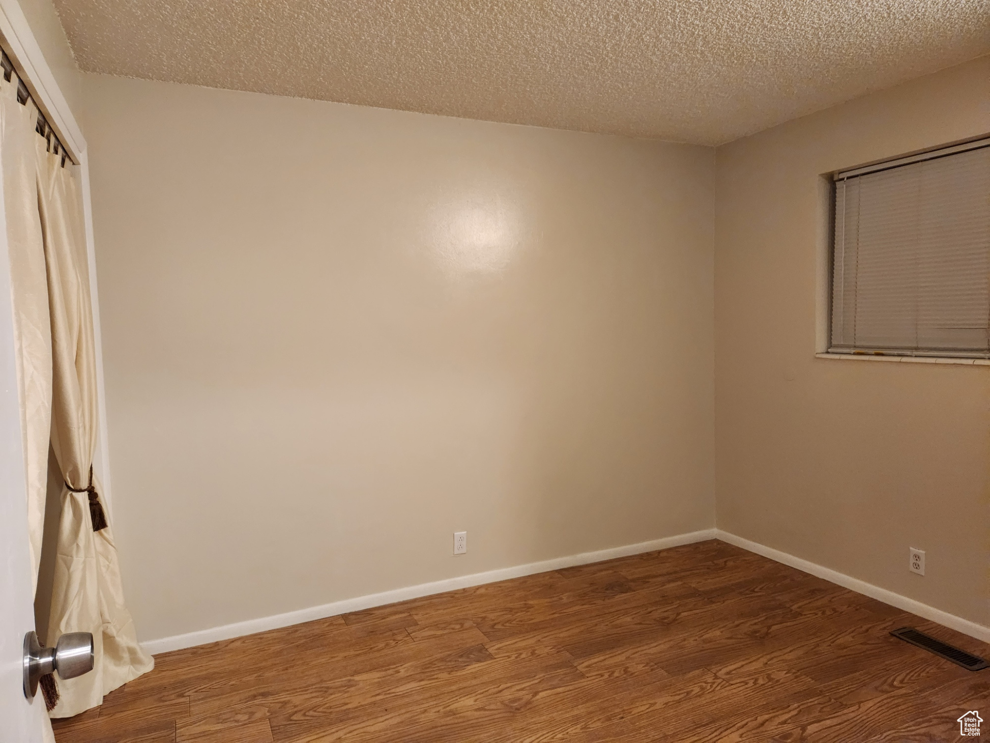 Spare room with dark hardwood / wood-style floors and a textured ceiling