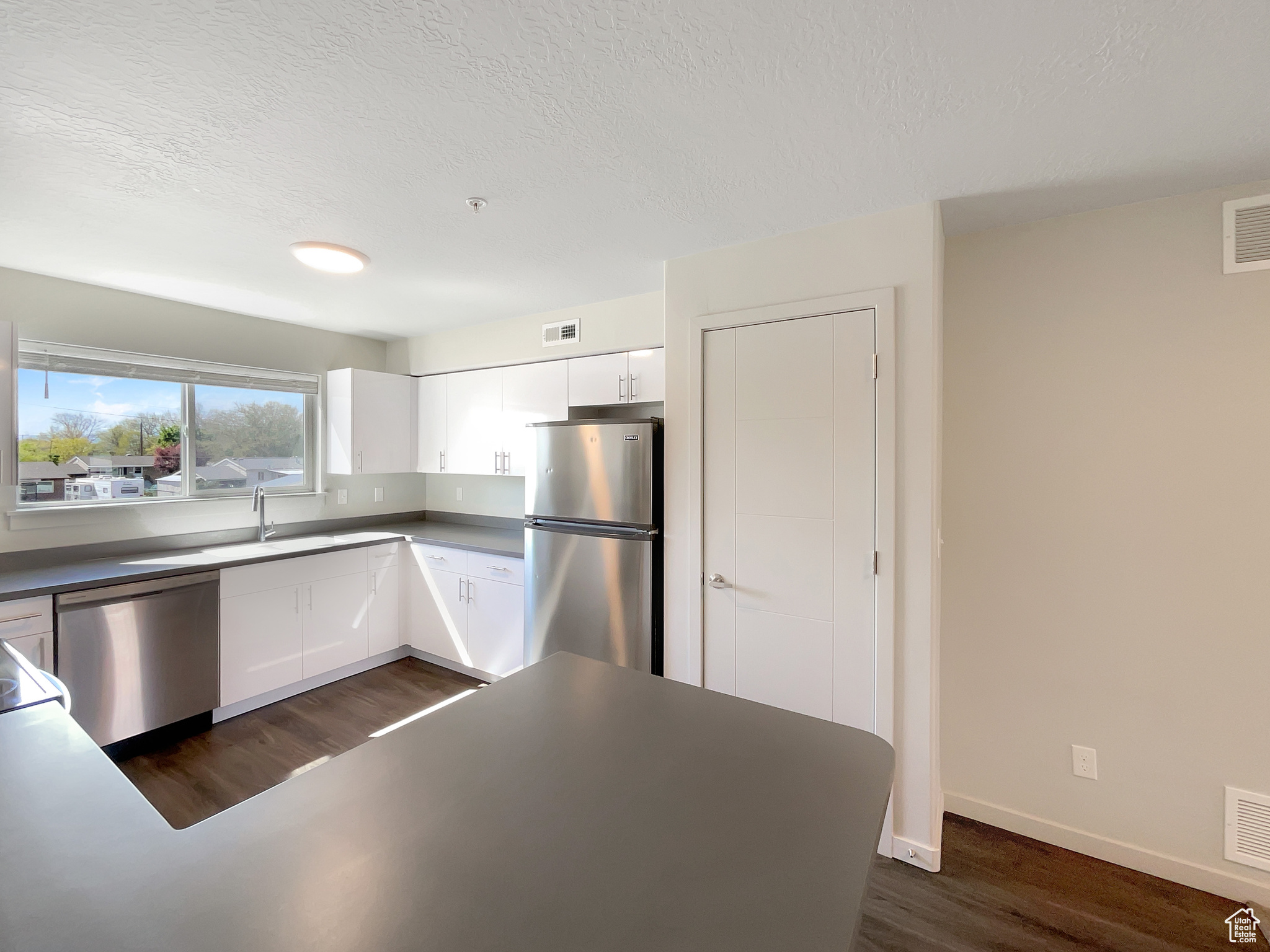 Kitchen featuring sink, appliances with stainless steel finishes, white cabinetry, and dark wood-type flooring