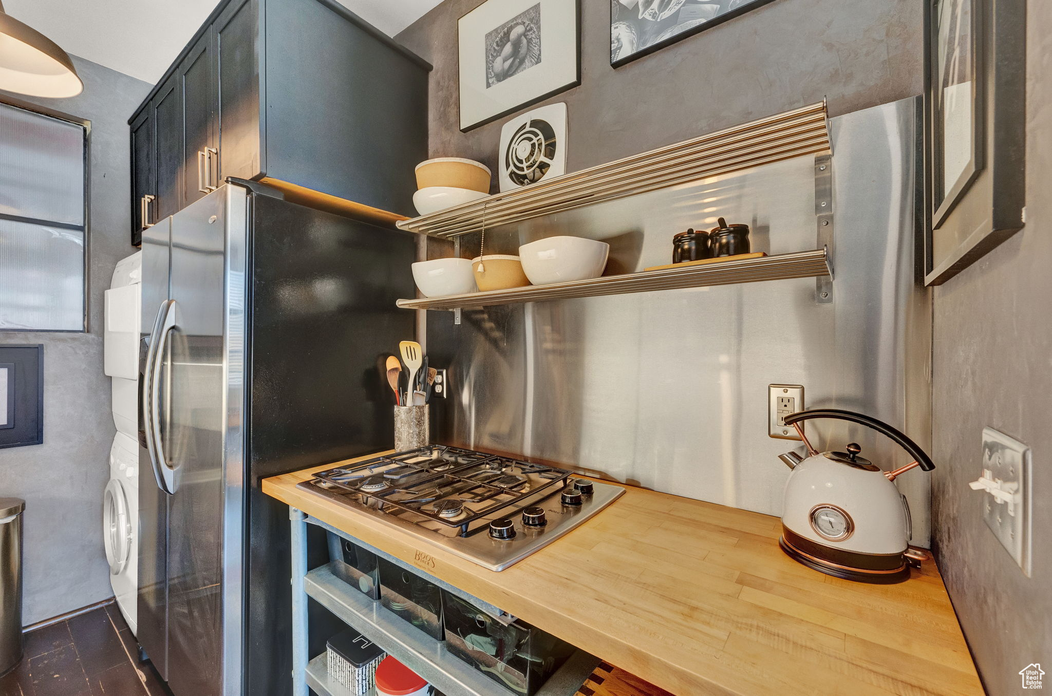 Kitchen featuring butcher block countertops, stacked washer / dryer, and stainless steel gas cooktop