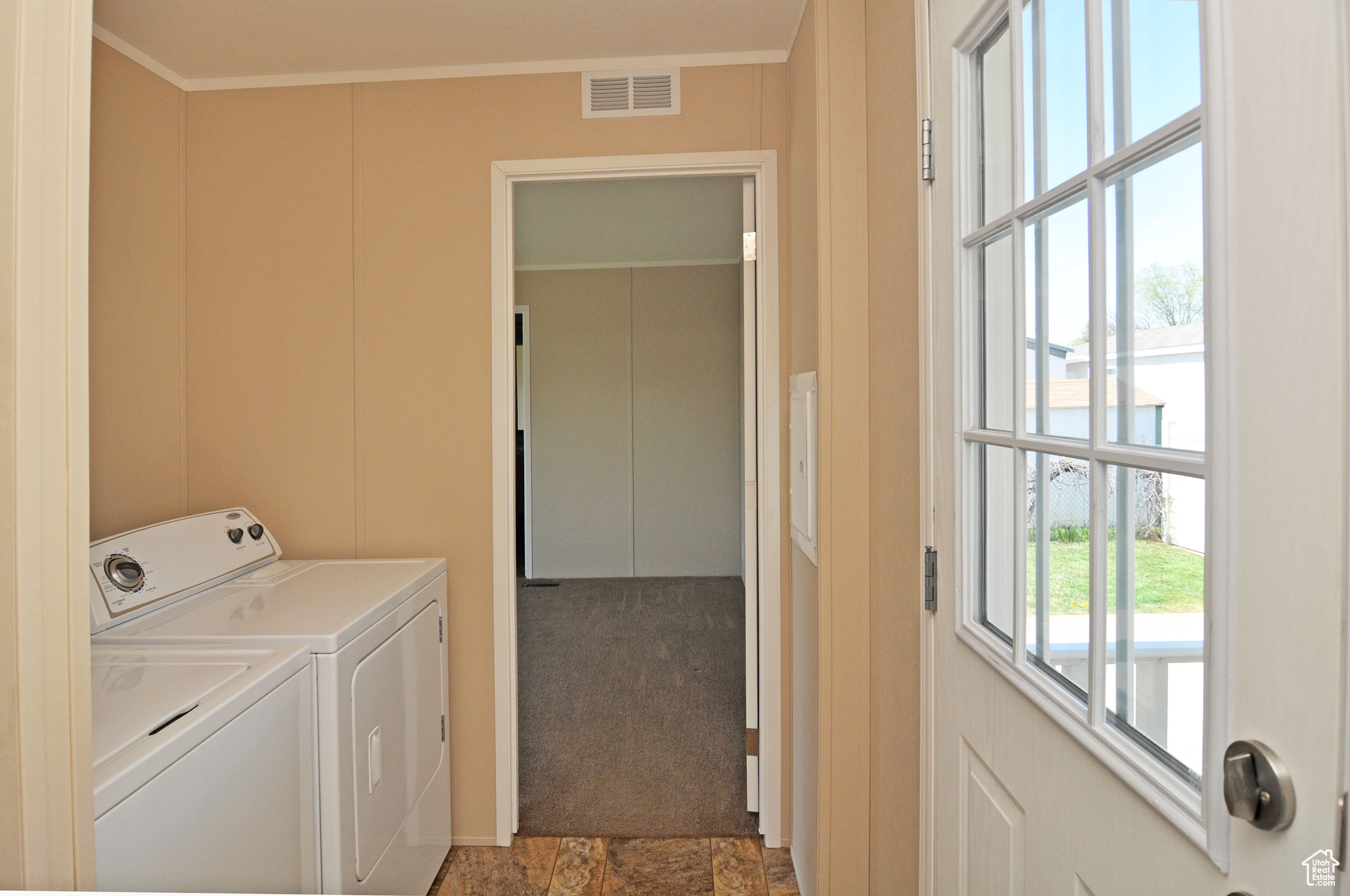 Clothes washing area featuring crown molding, light colored carpet, and washing machine and dryer