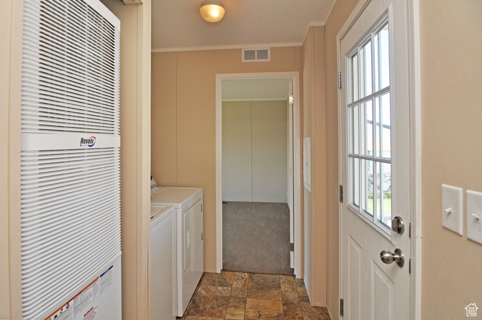 Laundry room featuring dark carpet, crown molding, and washing machine and clothes dryer