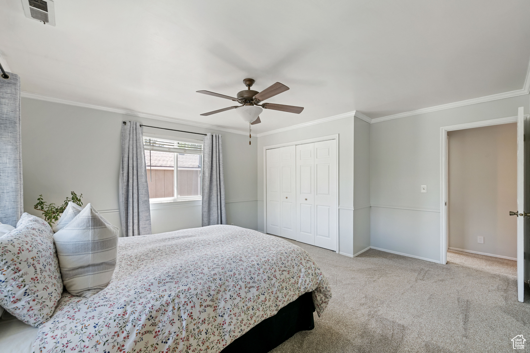 Bedroom with carpet flooring, a closet, crown molding, and ceiling fan