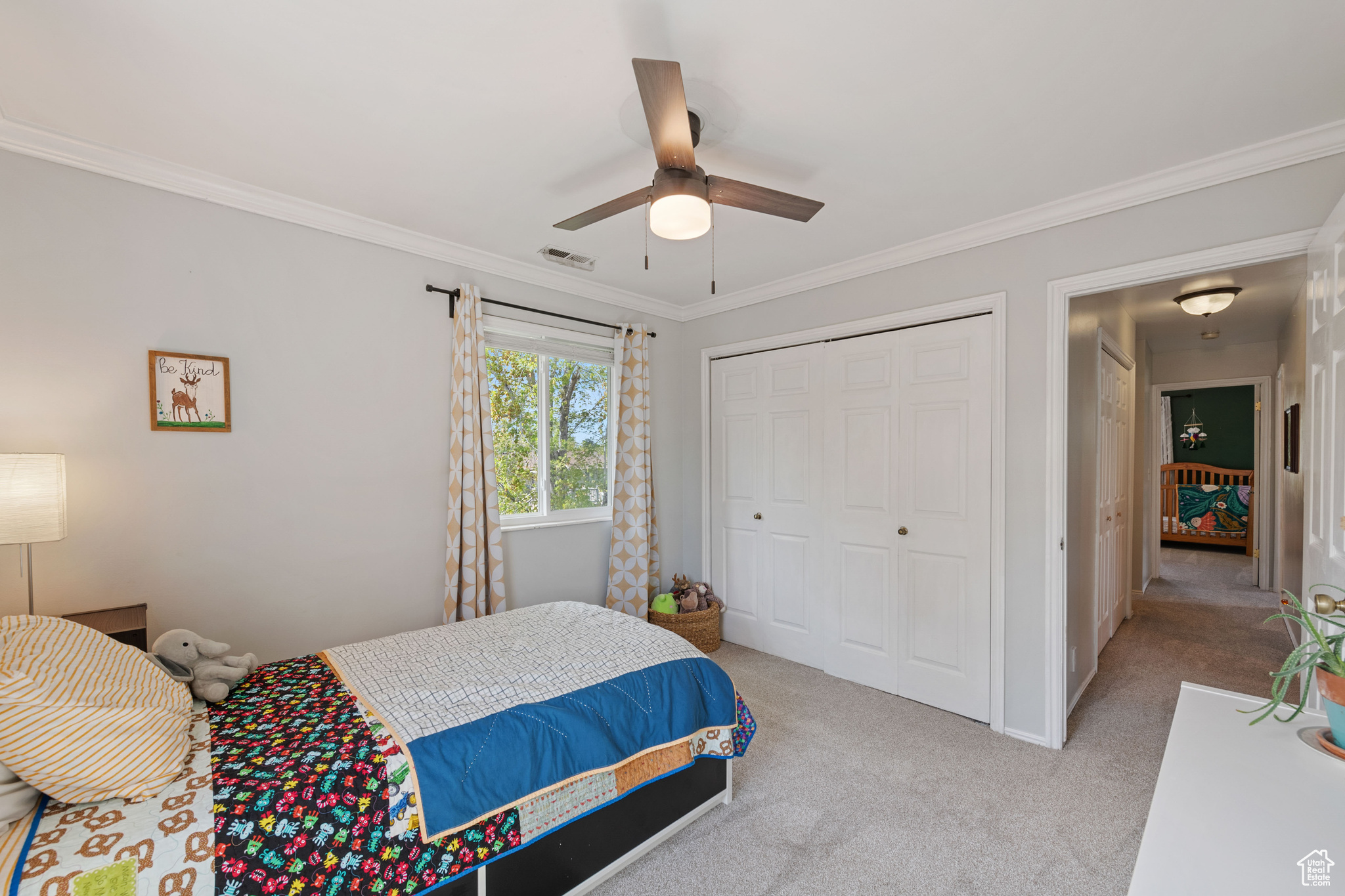 Bedroom with a closet, ornamental molding, ceiling fan, and carpet flooring